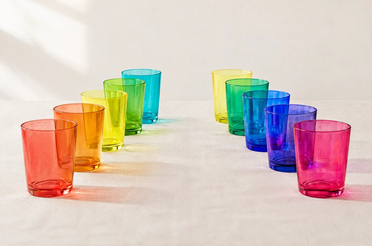 Deux rangées de verres colorés traversés par la lumière : à gauche corail, mandarine, citron et lime, à droite rose shocking, violet et bleu électriques